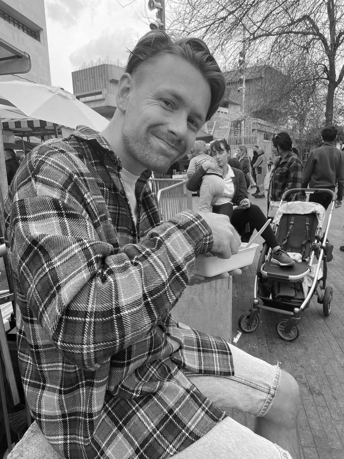 Tom smiling while sitting outside at a market