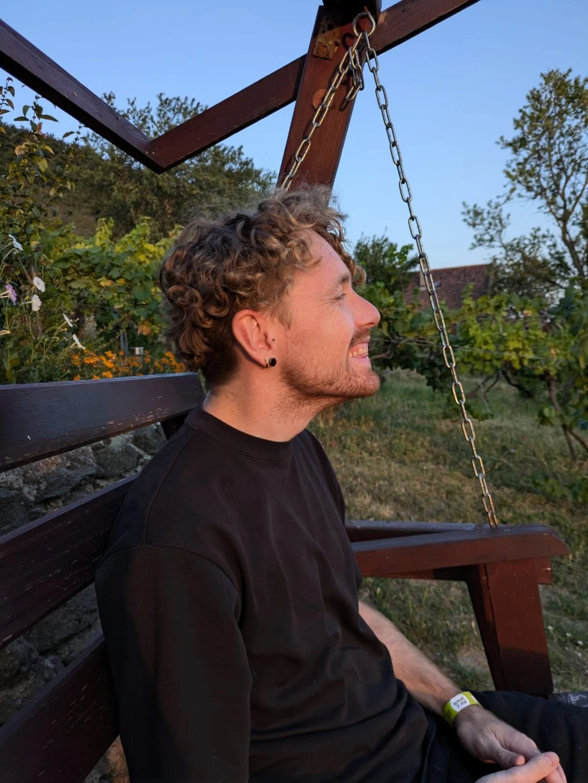 Tom smiling while sitting on a garden swing at sunset